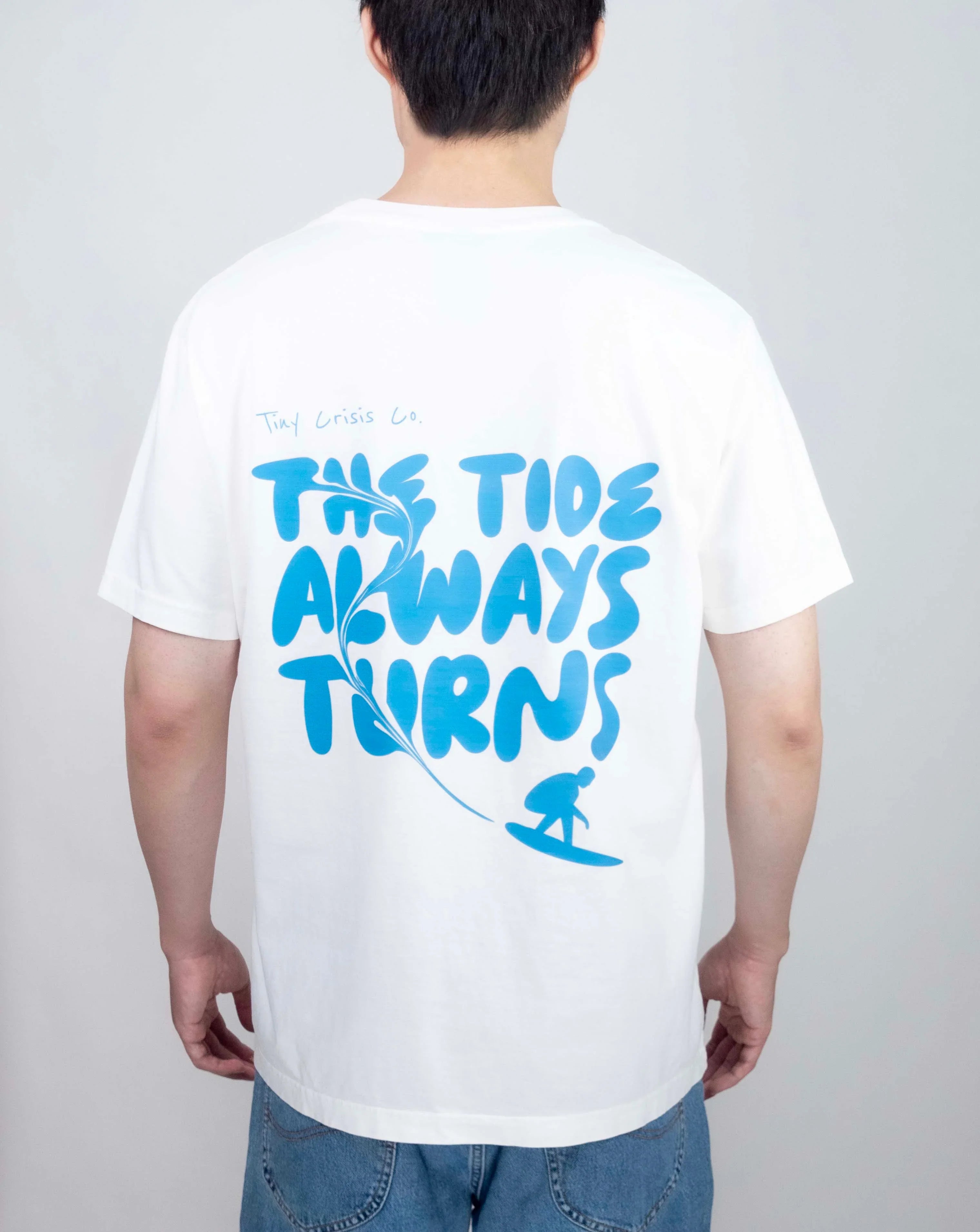 Person wearing a white t-shirt with blue text and graphics on a plain background