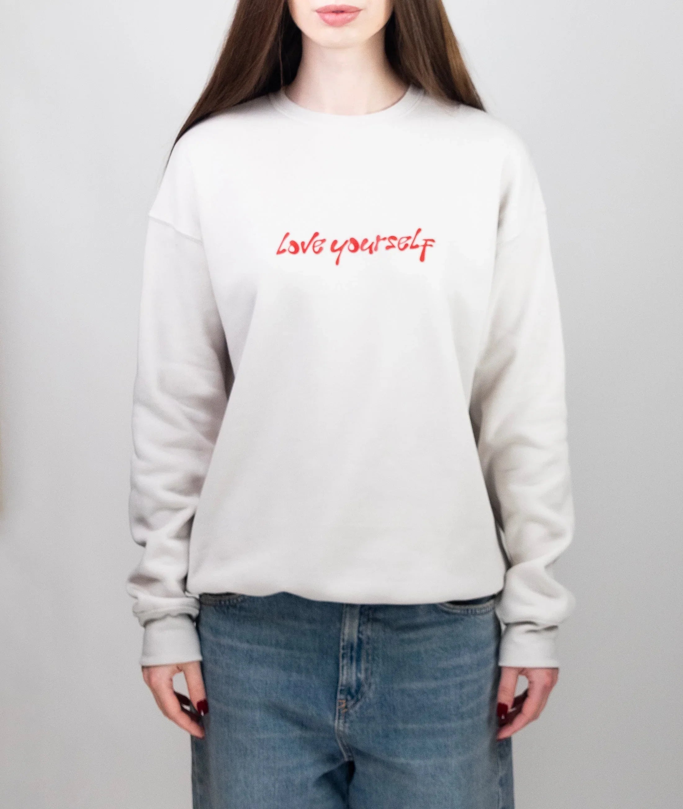 Person standing in "Love Yourself" Beige crewneck on plain background