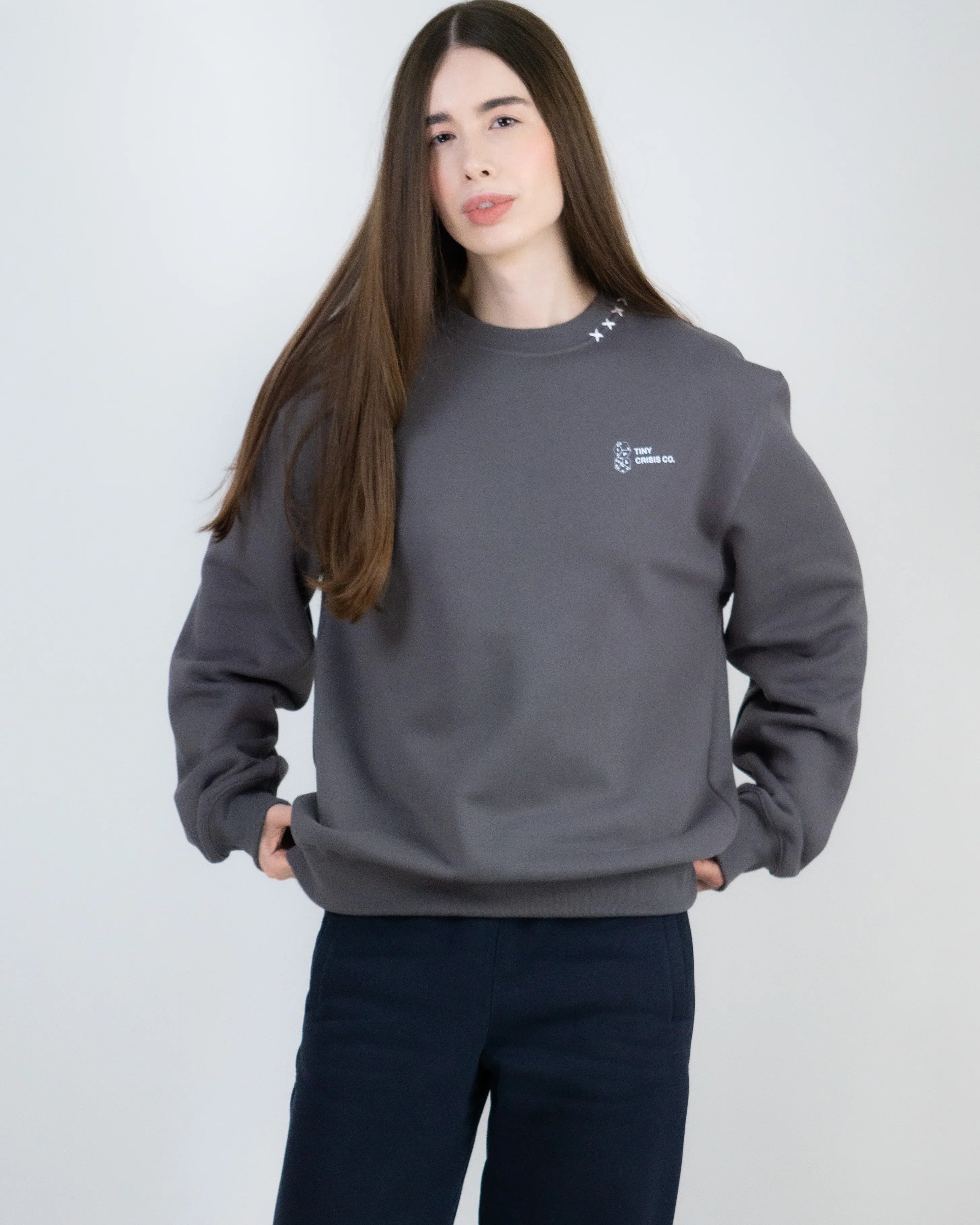 Person wearing a gray sweatshirt with a small logo on a light gray background