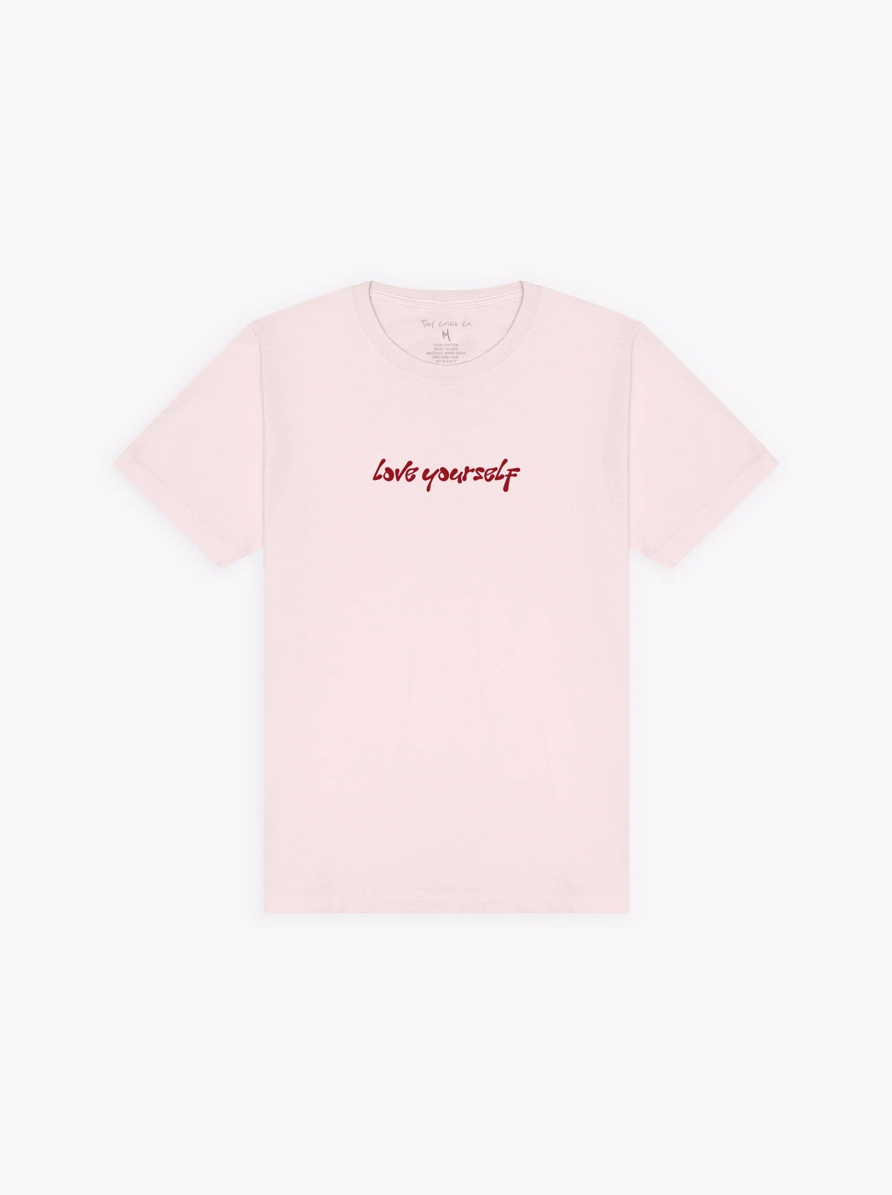 Pink t shirt saying "love yourself" in red handwritten font on the chest on plain white background