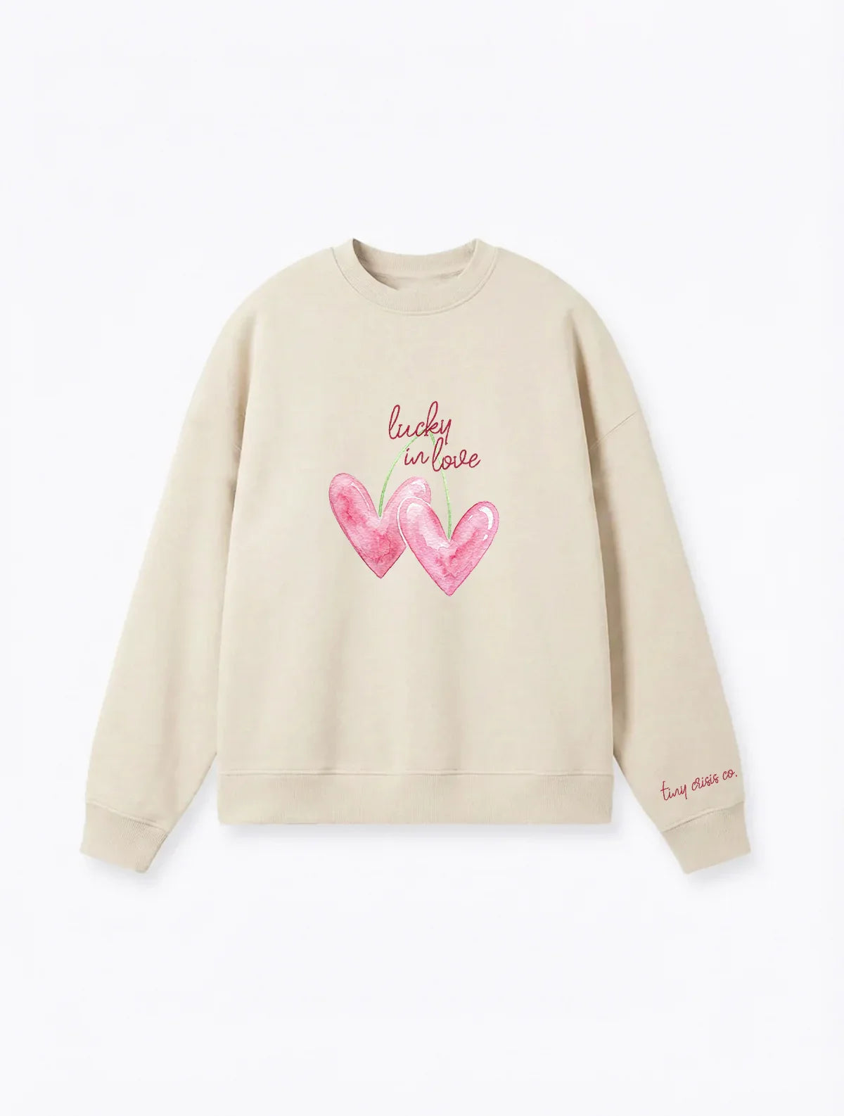 Beige crewneck with "cherry hearts" print that says "Lucky in love" on plain white background