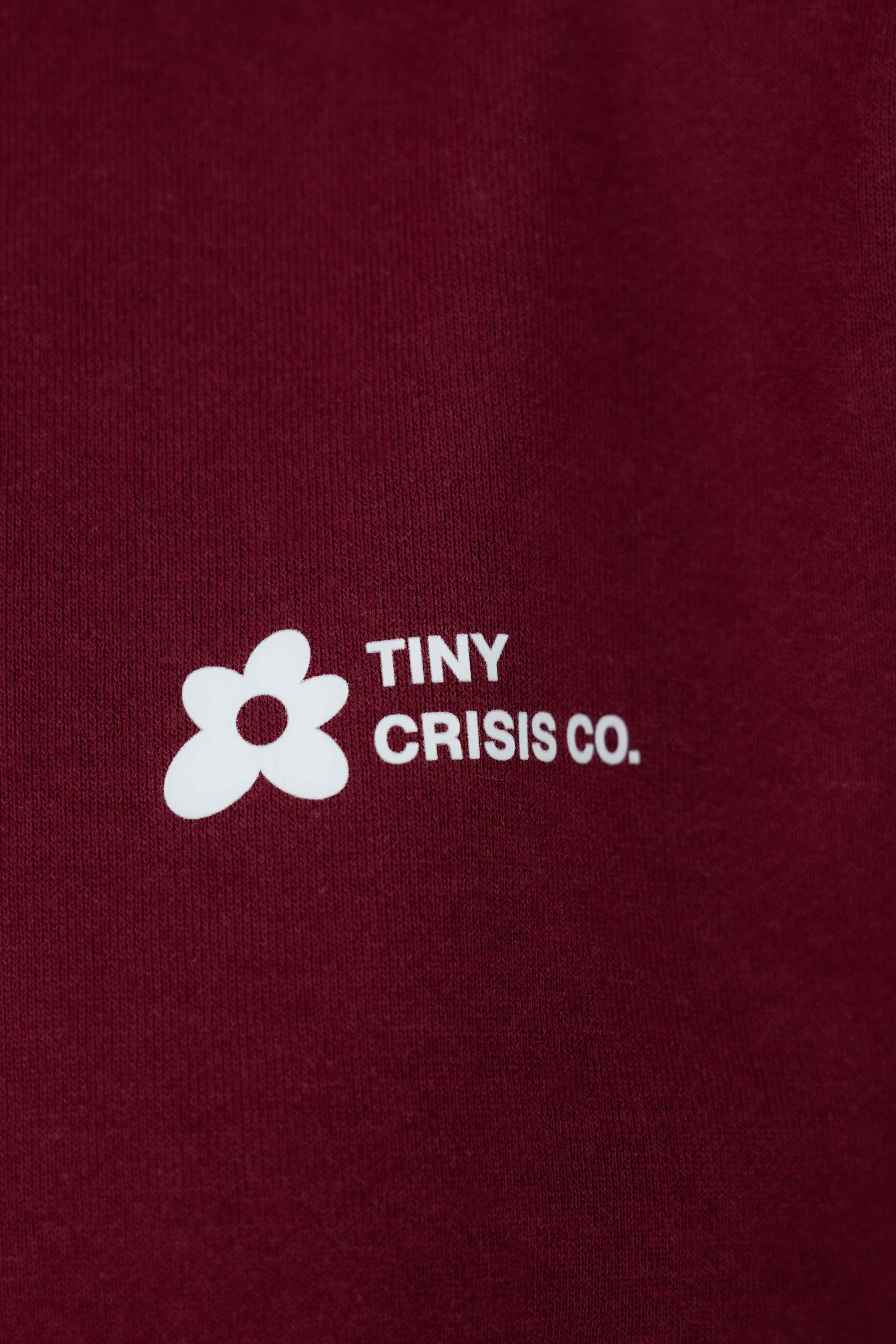 Maroon shirt with 'Tiny Crisis Co.' logo in white