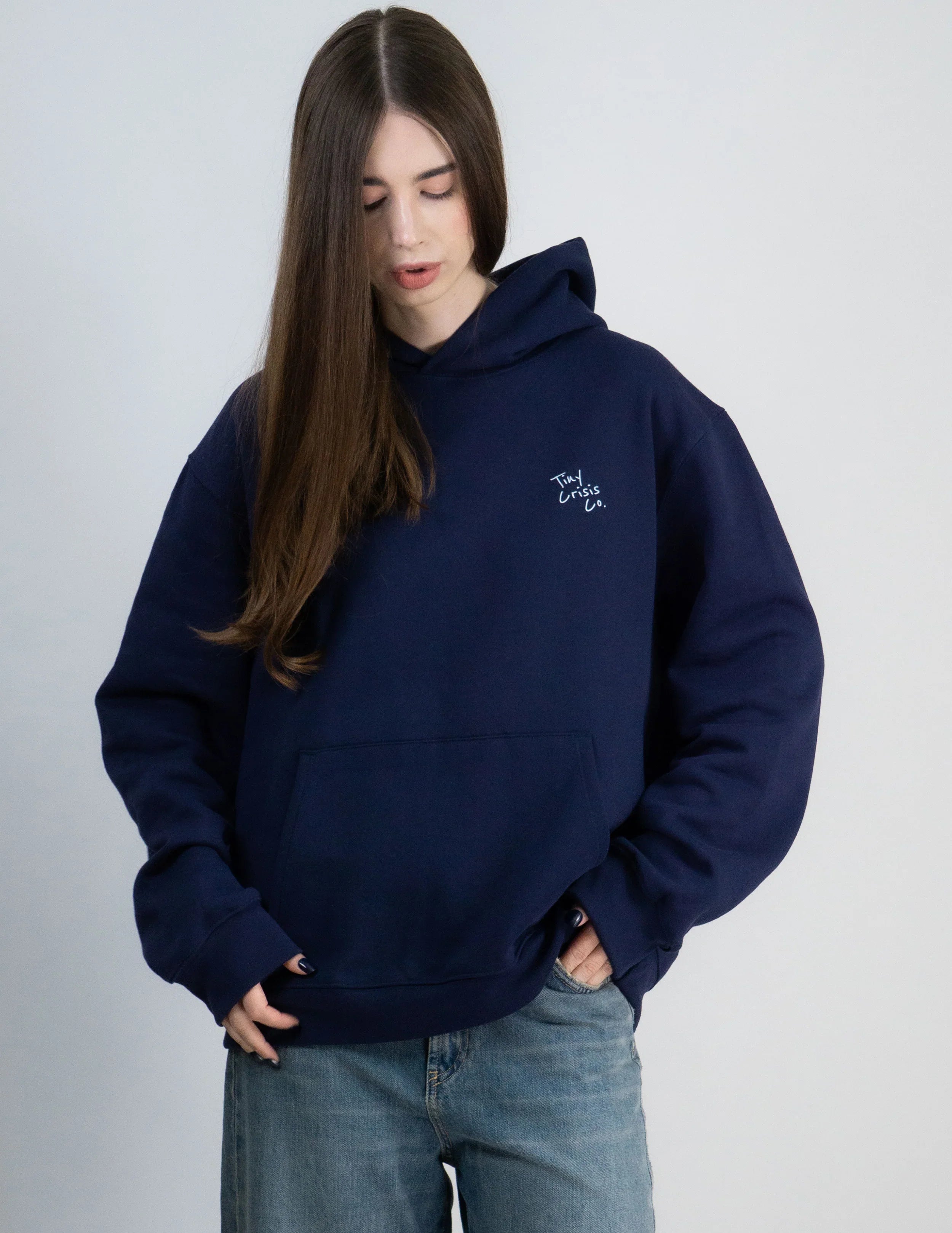 Person wearing a navy blue hoodie with a logo on a plain background