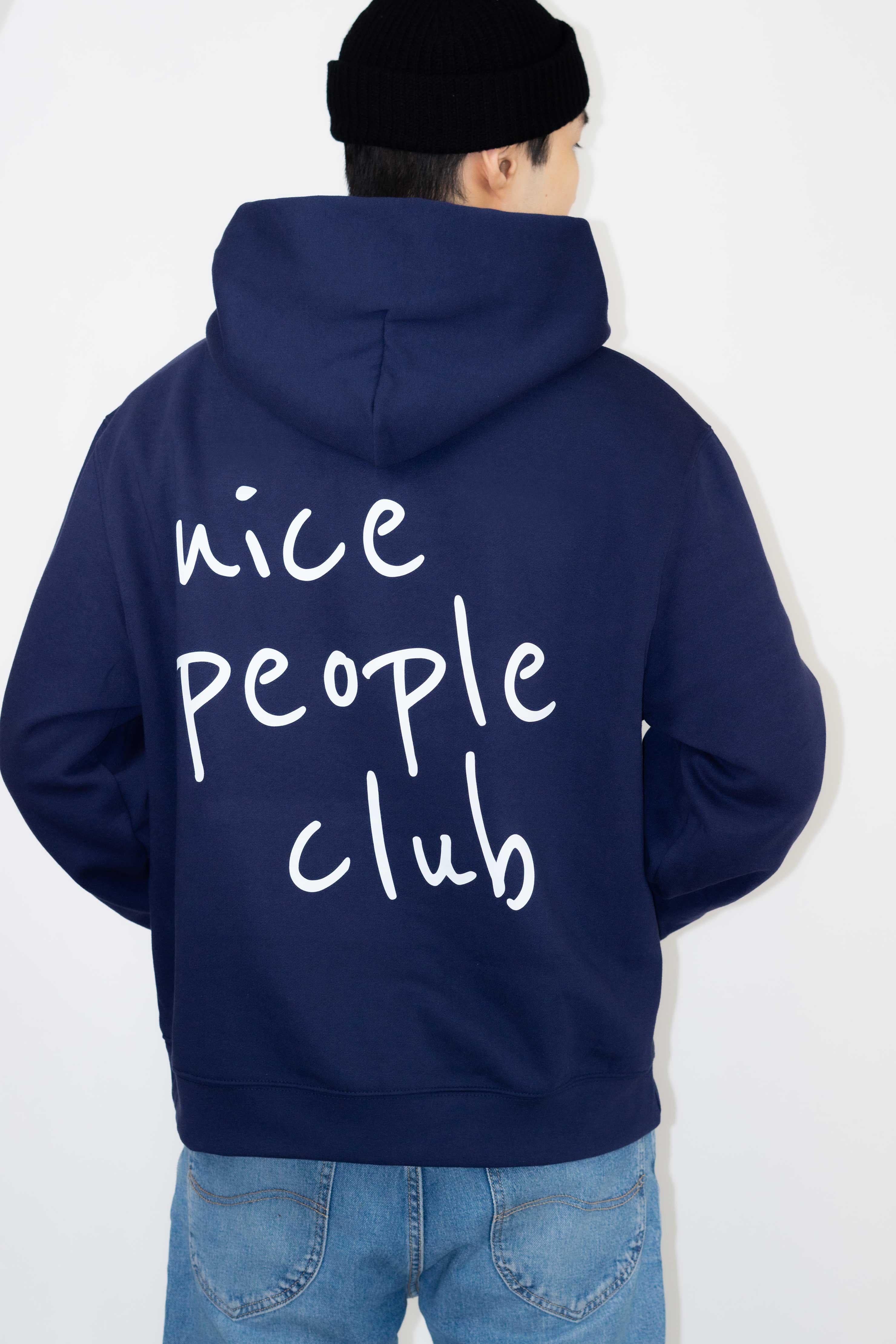 Person wearing a navy hoodie with 'nice people club' text on the back against a white background
