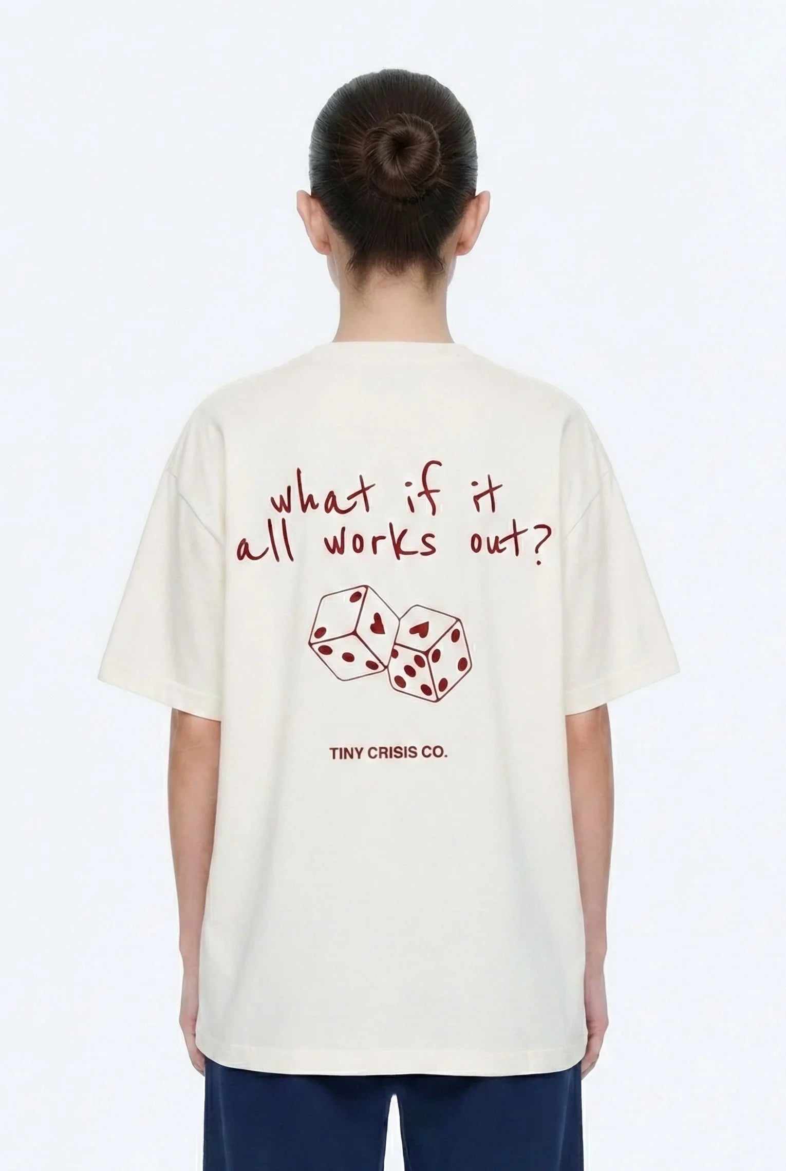 Person wearing a white t-shirt with text and dice design, standing against a white background